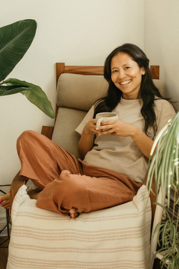 Chandni Karmacharya smiling while holding a mug, sitting in a cozy chair.